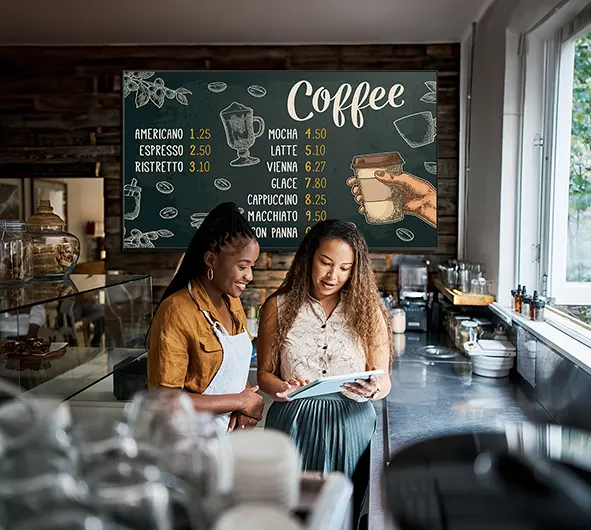A large display broadcasting a menu within a coffee shop