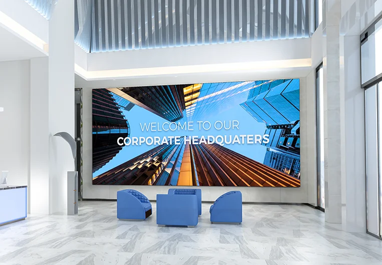 A bright, modern corporate lobby featuring a massive digital display wall showing skyscrapers and the text "WELCOME TO OUR CORPORATE HEADQUARTERS."
