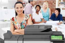 Group of people around a table and a woman standing in front of an MFP