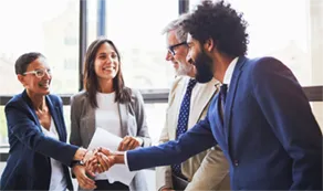Man and woman shaking hands in front of group of others