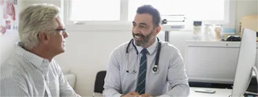 Image of a doctor speaking to a male patient in a doctor's office 