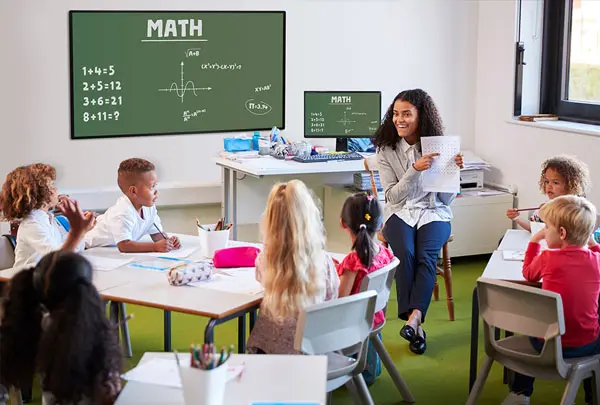 a classroom of young children with a teacher with a math equation on the display