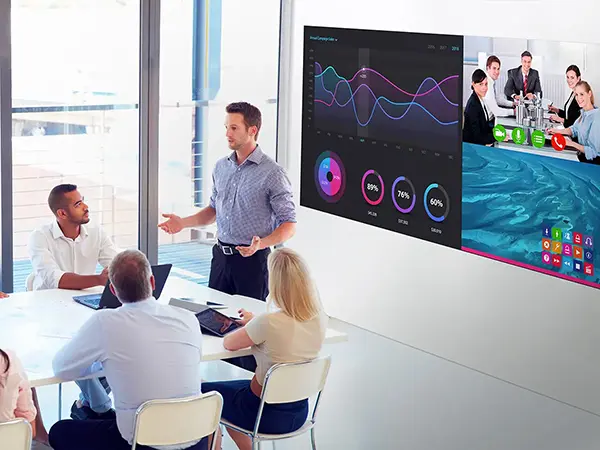 Man giving a hybrid presentation in front of an LED display in a conference room