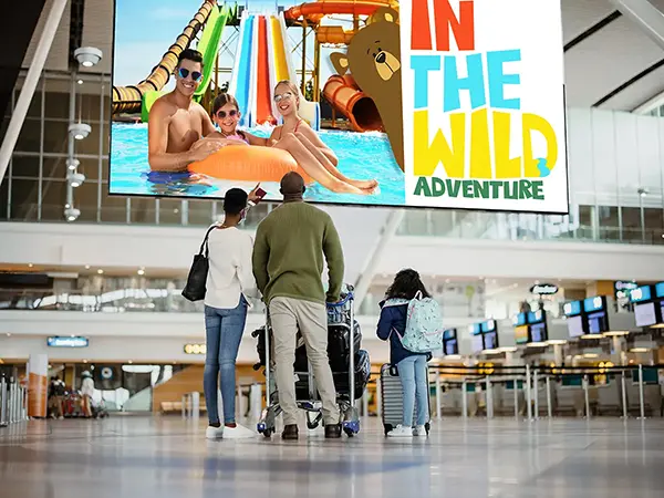 A family looks up at an advertisement for a water park on a display in the airport