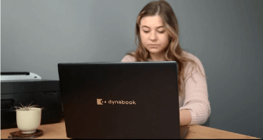 Woman sitting at a table and using a Dynabook laptop