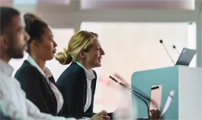 Three workers sitting at a desk in front of microphones