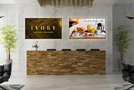 Lobby showing reception desk with two displays showing advertisements on the wall behnd it
