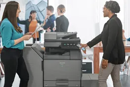 Two women standing in front of a copier