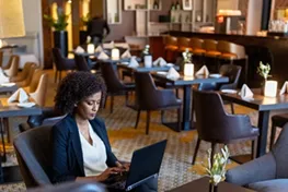 Woman sitting at a table in a restaurant working on a laptop