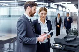 Man woman standing in front of a copier reading a document