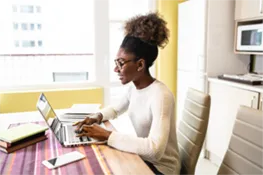 Woman sitting at a table in an office working on a laptop