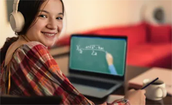 Image of a young student wearing headphones working on a laptop computer
