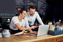 Woman sitting at a table in a restaurant working on a laptop