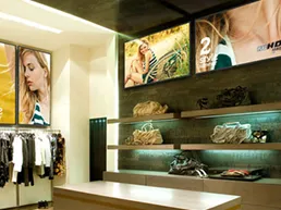 Clothes rack, display counters and digital signs on a wall inside a store