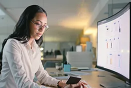Woman sitting working on a large computer montior