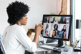 Woman sitting in front of a computer with images of multiple people on it