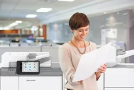 Woman standing in front of a copier reading a documemt