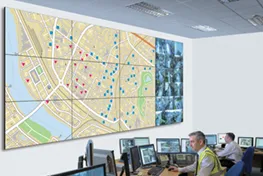 Room with a very large wall digital display and men sitting at computers