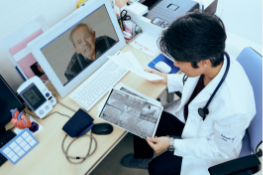 Doctor sitting in front of a computer displaying a video of a patient