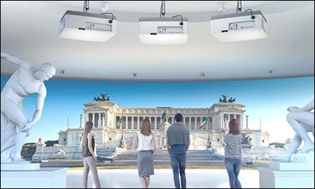 group of people in a museum with 3 projectors on ceiling